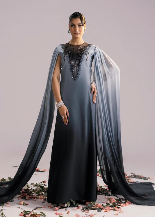 Woman wearing a long, elegant dress with a cape on a light gray background