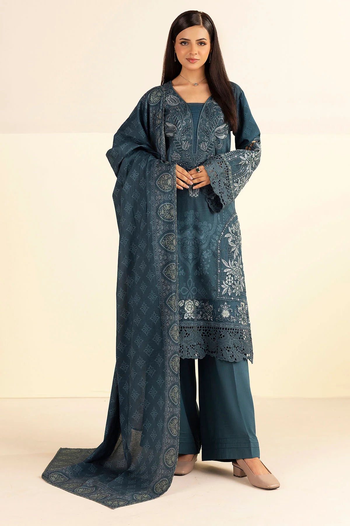 Woman wearing a blue embroidered traditional outfit on a beige background