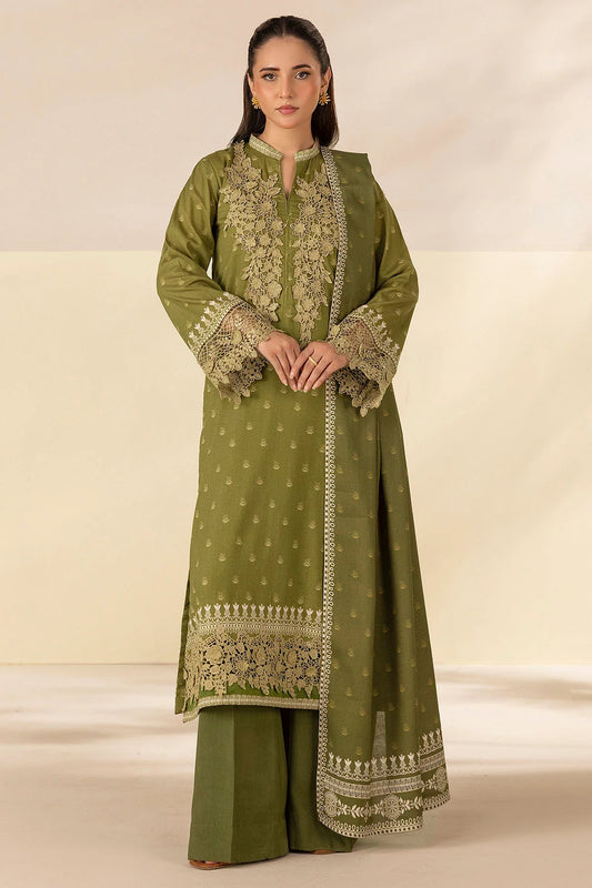 Woman wearing a green traditional outfit with intricate embroidery on a plain background